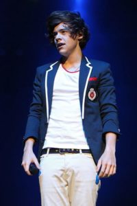 Harry performing on April 2012 looking like a (very cute!) schoolboy with a navy blazer with white piping, and white pants and tee. Photo by: Getty Images